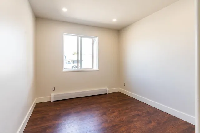 an empty room with wooden floor and window