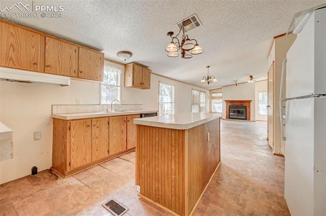 2259 Pathfinder Road Florissant, CO 80816 - Photo 17 of 33 Kitchen with hanging light fixtures, white refrigerator, light tile patterned floors, sink, and a notable chandelier