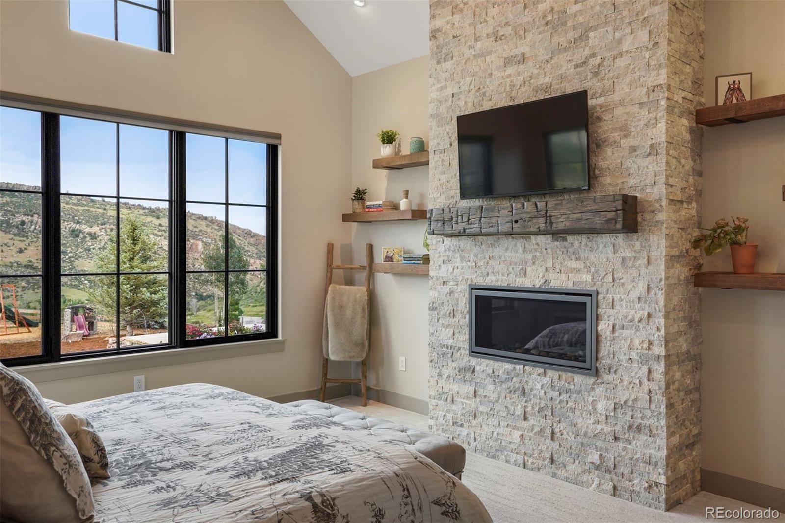 15411 Dinosaur Ridge Road Morrison, CO 80465 - Photo 19 of 50 a bedroom with a bed and a flat screen tv