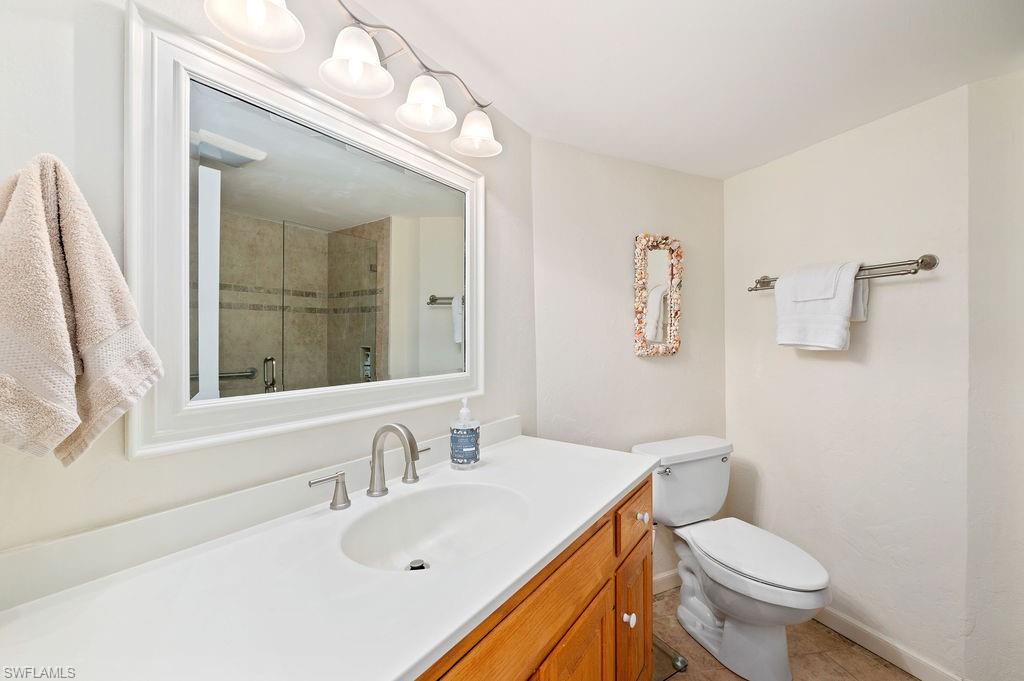 415 Augusta Boulevard, Unit 309 Naples, FL 34113 - Photo 13 of 36 a bathroom with a sink a toilet and a mirror