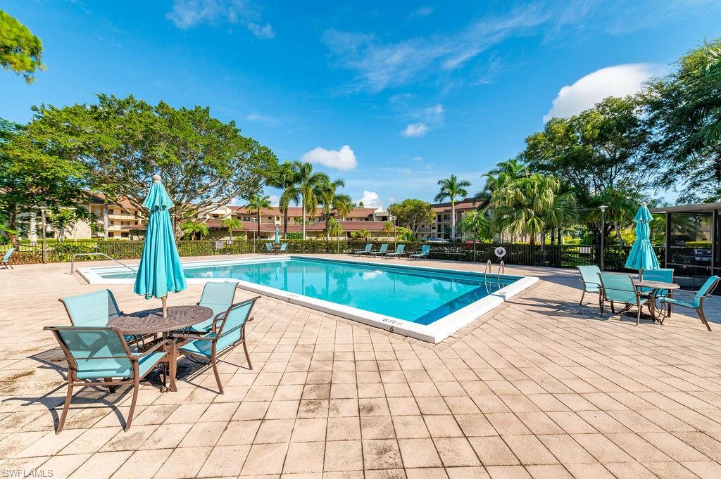 415 Augusta Boulevard, Unit 309 Naples, FL 34113 - Photo 31 of 36 a view of a swimming pool with lounge chair and trees in the background