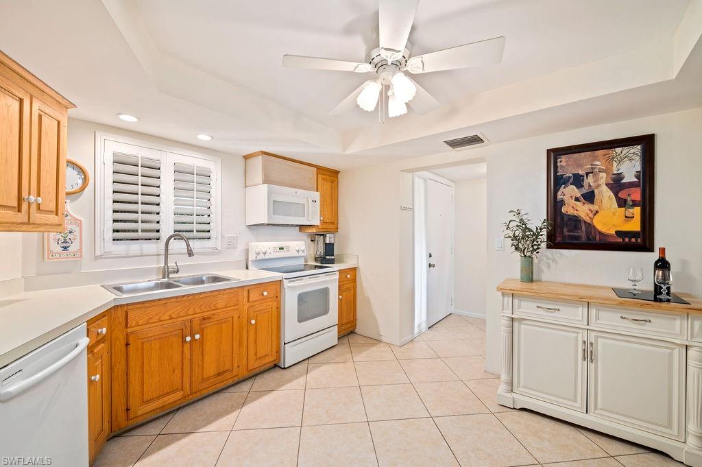 415 Augusta Boulevard, Unit 309 Naples, FL 34113 - Photo 7 of 36 a large white kitchen with kitchen island granite countertop a stove a sink a dining table and chair