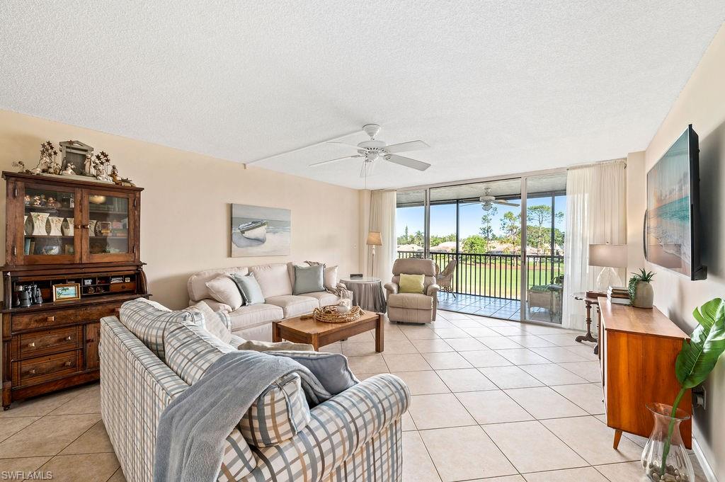 415 Augusta Boulevard, Unit 309 Naples, FL 34113 - Photo 10 of 36 a living room with furniture a flat screen tv and a floor to ceiling window