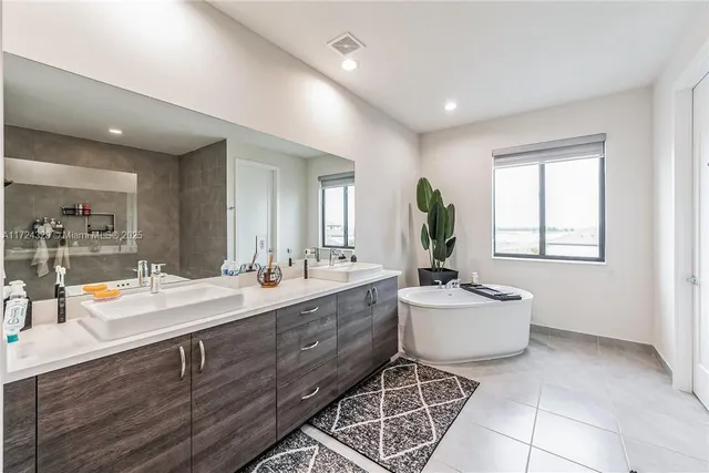 a spacious bathroom with a double vanity sink mirror and bathtub