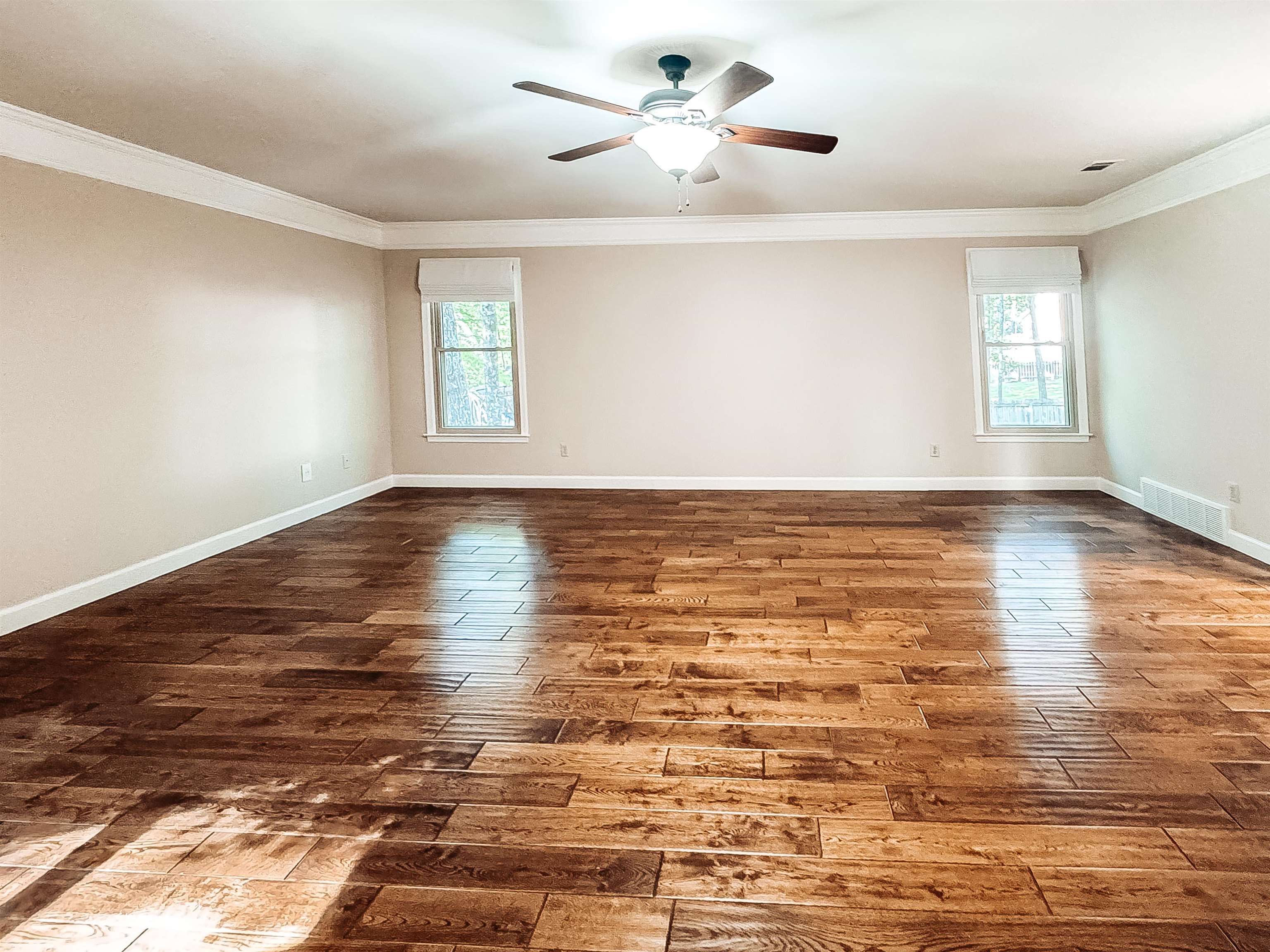 832 South Tree Drive Collierville, TN 38017 - Photo 27 of 40 Spacious room featuring rich wood-finish flooring, two large windows with white shades, and a ceiling fan with integrated lighting