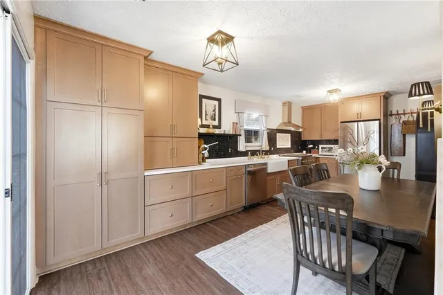 a kitchen with a refrigerator a sink dishwasher a dining table and chairs with wooden floor