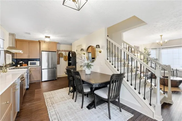 a kitchen with stainless steel appliances kitchen island granite countertop a dining table chairs and a refrigerator
