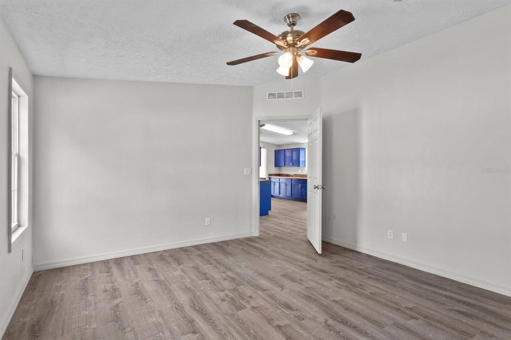 4793 Sunset Road St. Cloud, FL 34771 - Photo 13 of 28 an empty room with wooden floor and a ceiling fan