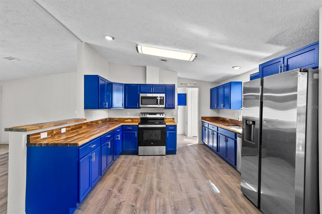 4793 Sunset Road St. Cloud, FL 34771 - Photo 9 of 28 a kitchen with stainless steel appliances granite countertop a stove a refrigerator and a wooden cabinets