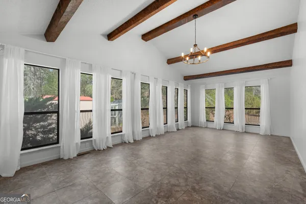 an empty room with windows and ceiling fan
