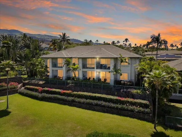 a front view of a house with a garden and lake view