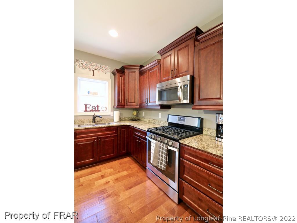 1187 Rays Bridge Road Whispering Pines, NC 28327 - Photo 14 of 35 a kitchen with stainless steel appliances granite countertop a stove top oven a sink and a microwave