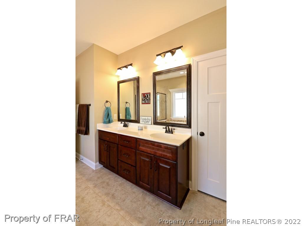 1187 Rays Bridge Road Whispering Pines, NC 28327 - Photo 18 of 35 a bathroom with a double vanity sink and a mirror