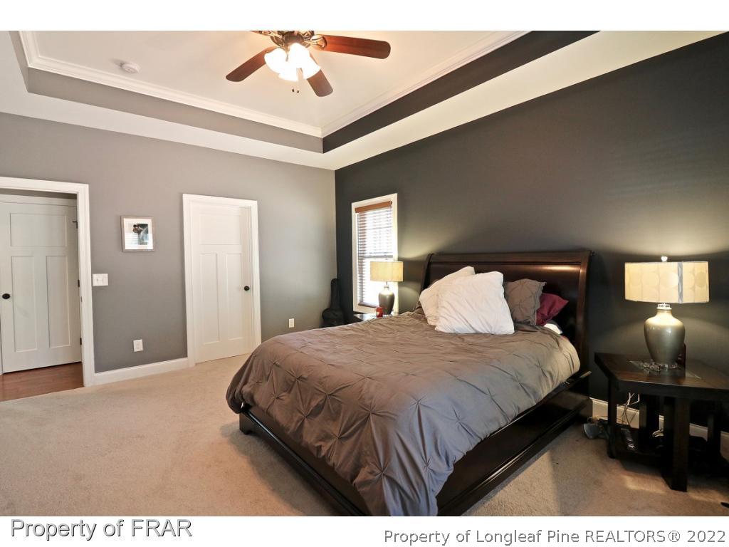 1187 Rays Bridge Road Whispering Pines, NC 28327 - Photo 19 of 35 a bedroom with a bed and a chandelier