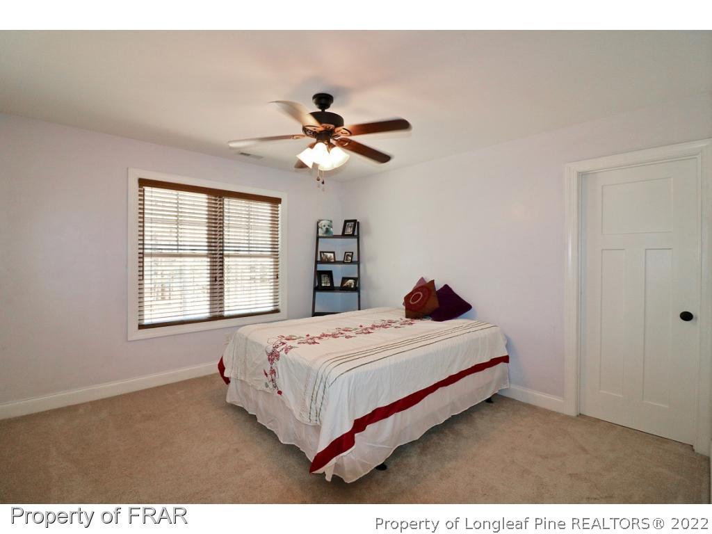 1187 Rays Bridge Road Whispering Pines, NC 28327 - Photo 26 of 35 a bedroom with a large bed and a chandelier