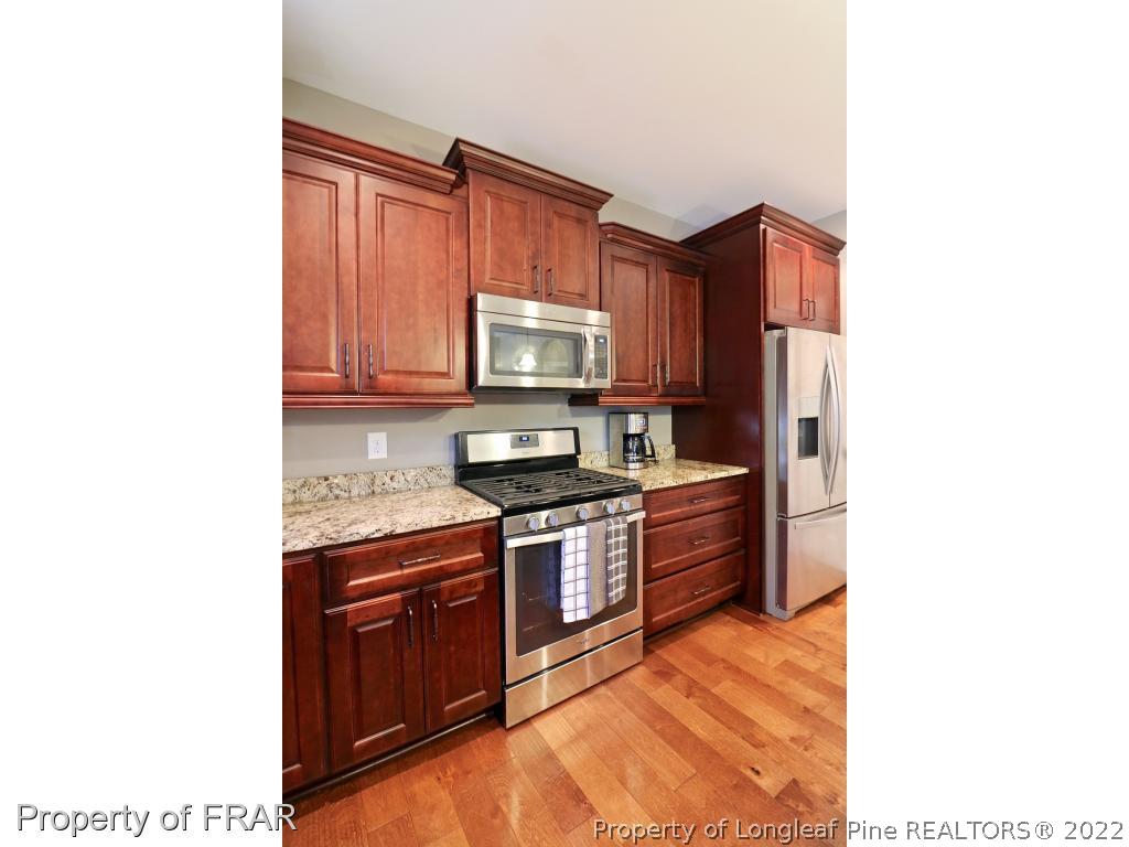 1187 Rays Bridge Road Whispering Pines, NC 28327 - Photo 32 of 35 a kitchen with stainless steel appliances granite countertop a stove top oven