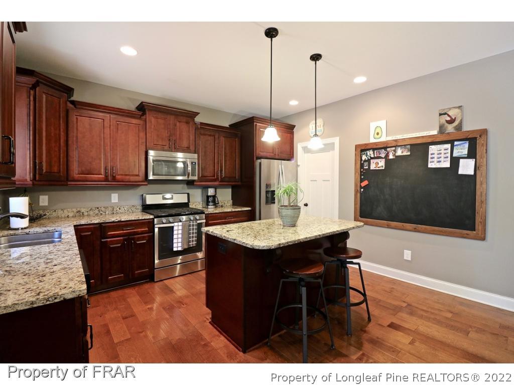 1187 Rays Bridge Road Whispering Pines, NC 28327 - Photo 4 of 35 a kitchen with kitchen island granite countertop wooden cabinets and a view of living room