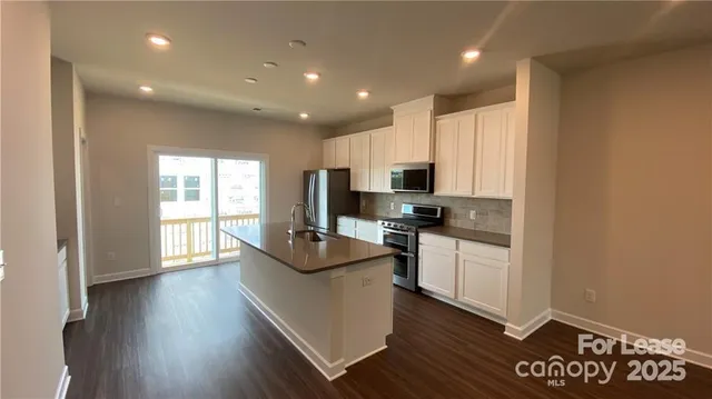 a kitchen with kitchen island granite countertop a sink cabinets and wooden floor
