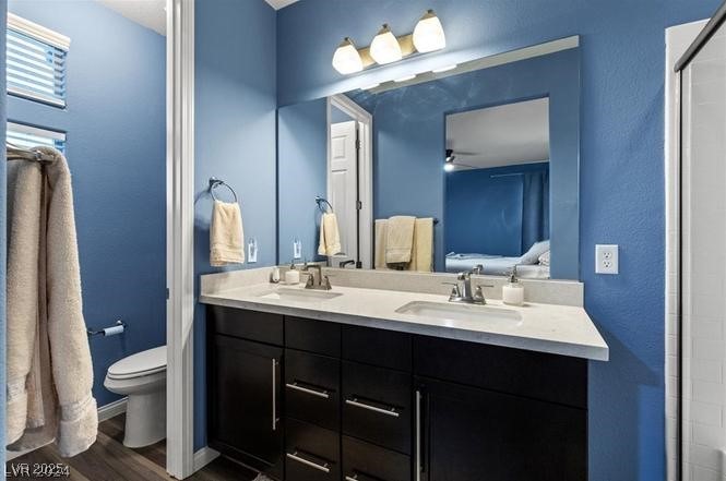 805 East Sunset Road Henderson, NV 89011 - Photo 24 of 43 Bathroom featuring double vanity, connected bathroom, wood finished floors, a shower, and a textured wall