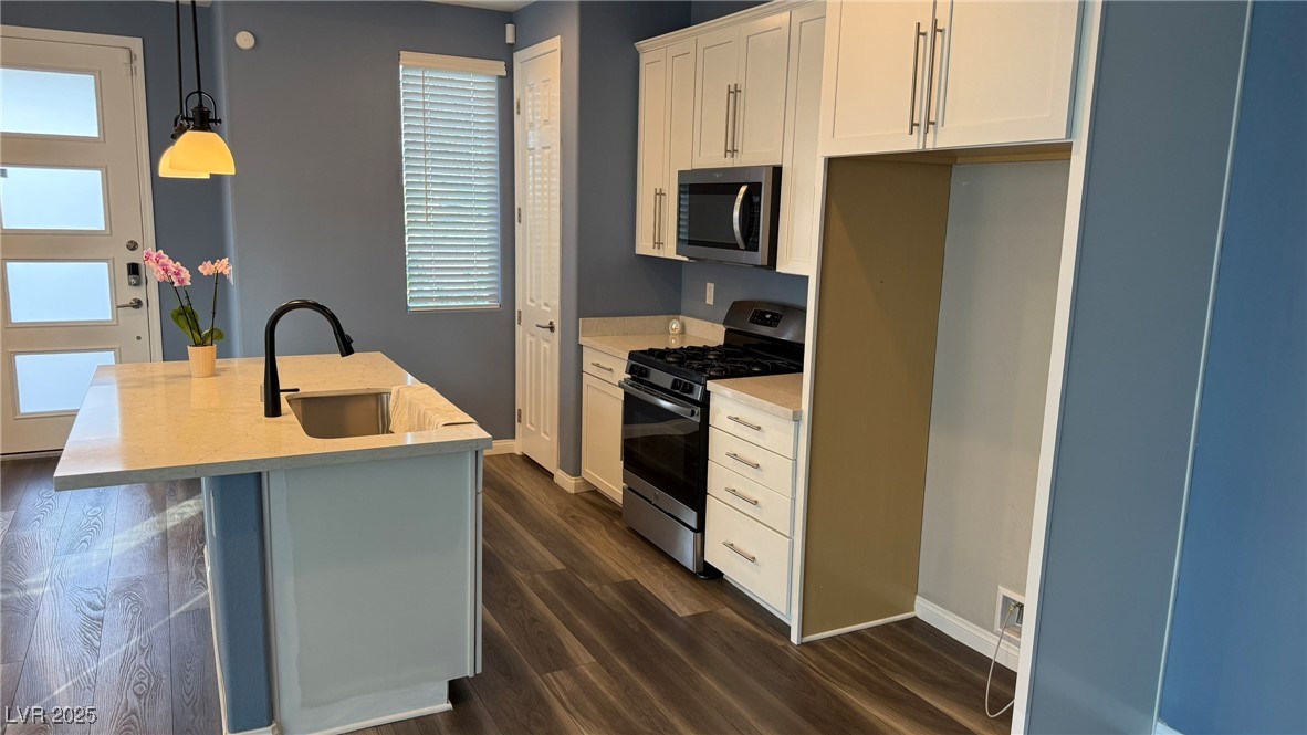 805 East Sunset Road Henderson, NV 89011 - Photo 42 of 43 Kitchen with stainless steel appliances, hanging light fixtures, dark wood-style floors, white cabinetry, and a kitchen island with sink