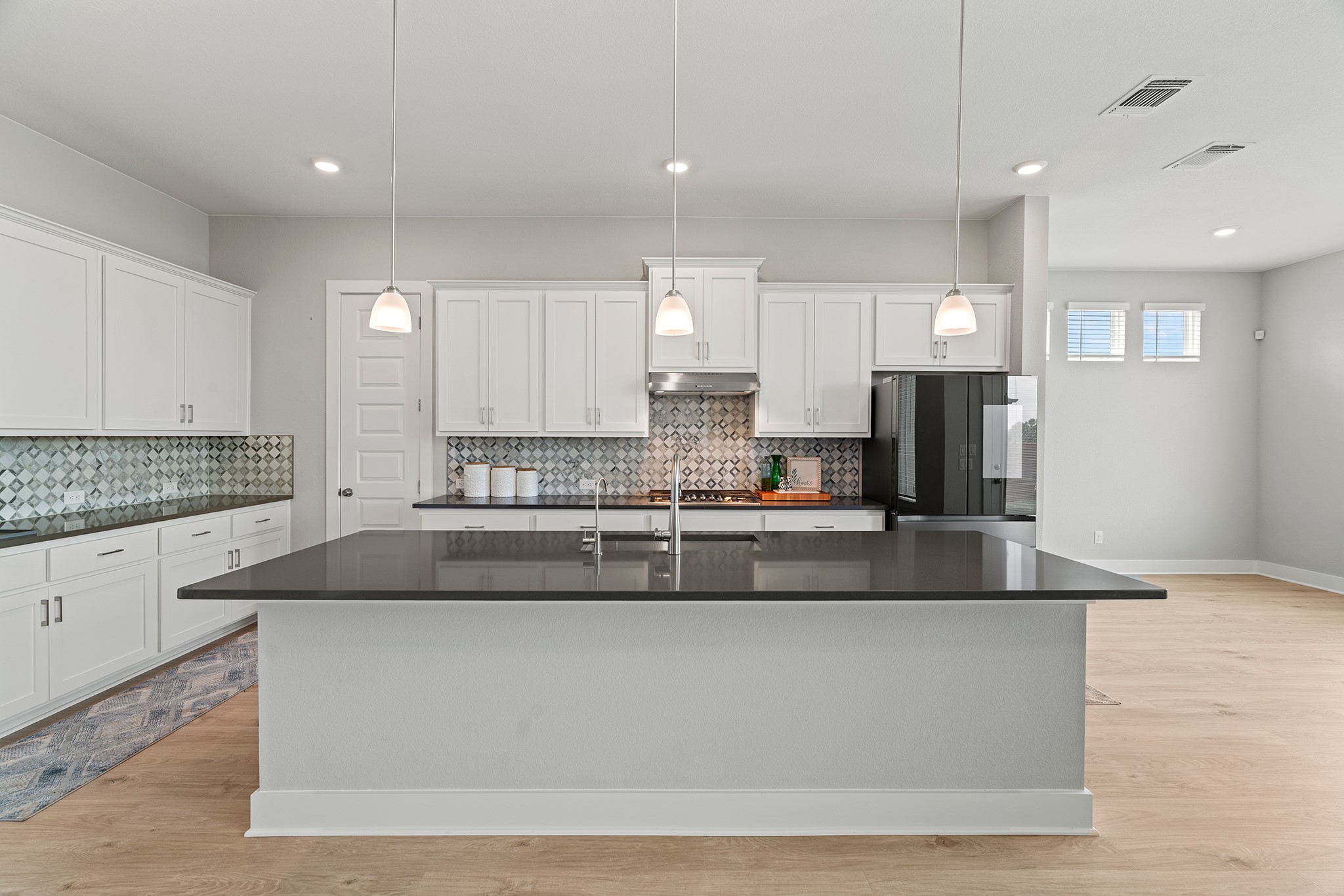 2112 Tobiano Trace Georgetown, TX 78633 - Photo 8 of 40 Kitchen with light wood-style flooring, decorative backsplash, a kitchen island with sink, and recessed lighting