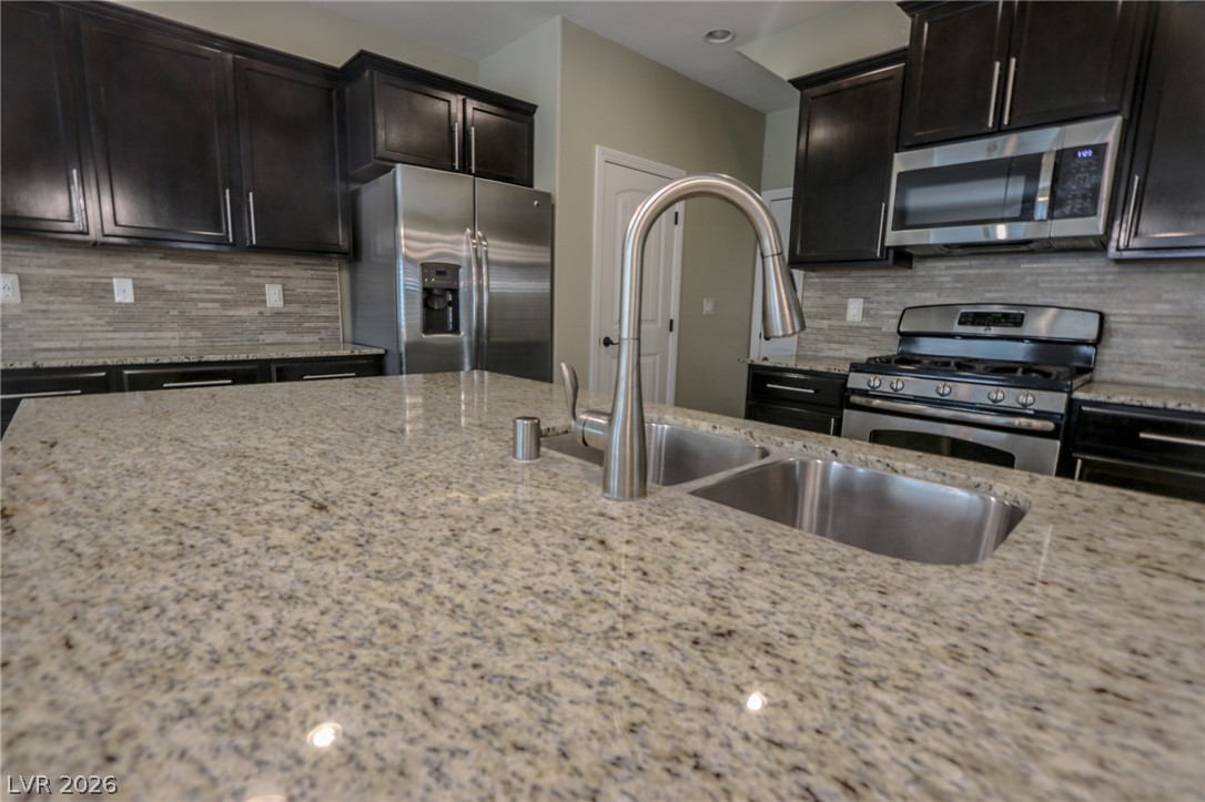Polished granite countertops surround a central sink alongside dark cabinetry in this kitchen.