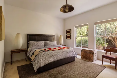 a bedroom with a bed a couch and a large window with balcony view