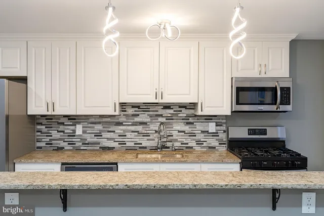 a kitchen with granite countertop a sink a stove and a microwave