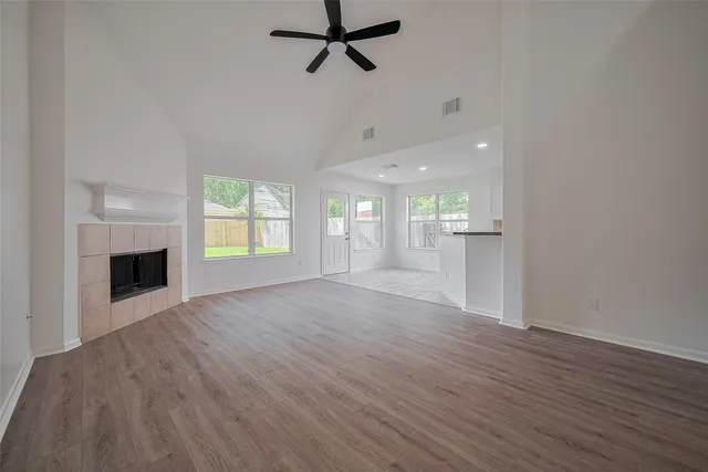 an empty room with wooden floor fireplace and windows
