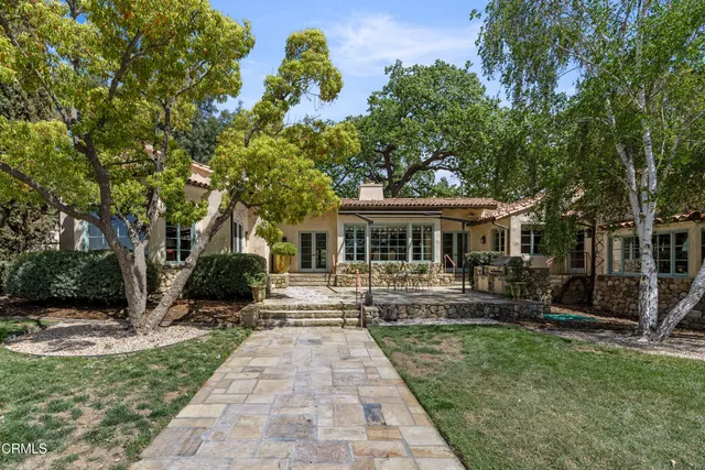 an aerial view of a houses with outdoor space and trees all around