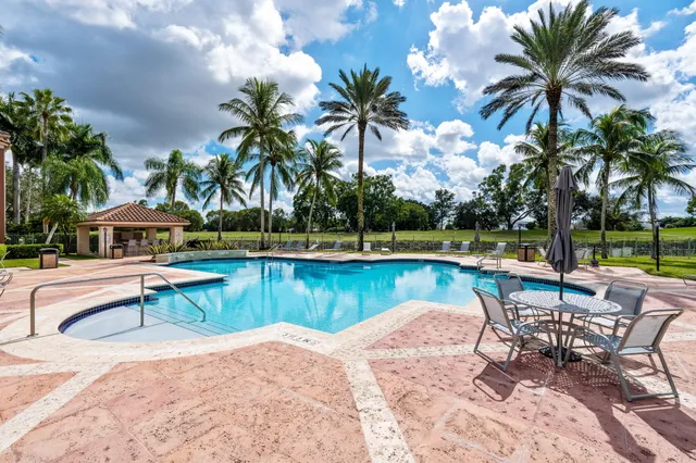 a view of a swimming pool with a lounge chair and palm trees