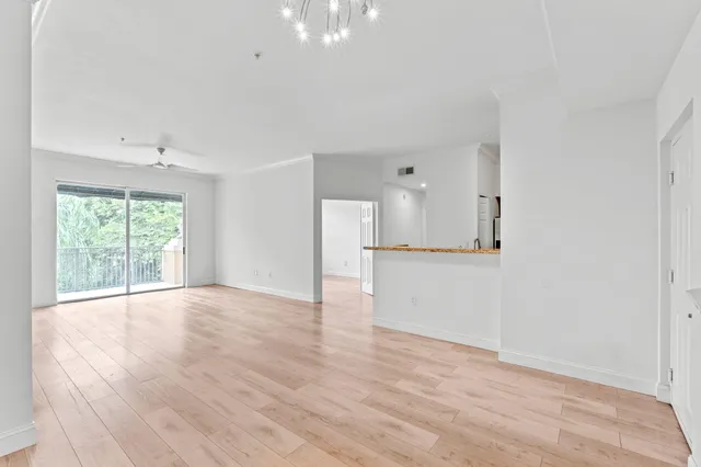 a view of empty room with wooden floor and kitchen view