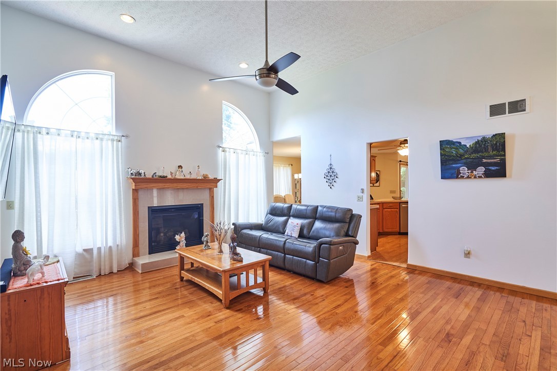 1963 Haines Road Madison, OH 44057 - Photo 3 of 34 Vaulted living room featuring a fireplace with a light wood mantel, high arched windows, recessed lighting, and wood-finish flooring
