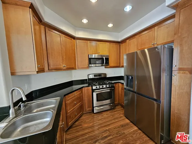 a kitchen with granite countertop stainless steel appliances a refrigerator stove top oven and sink