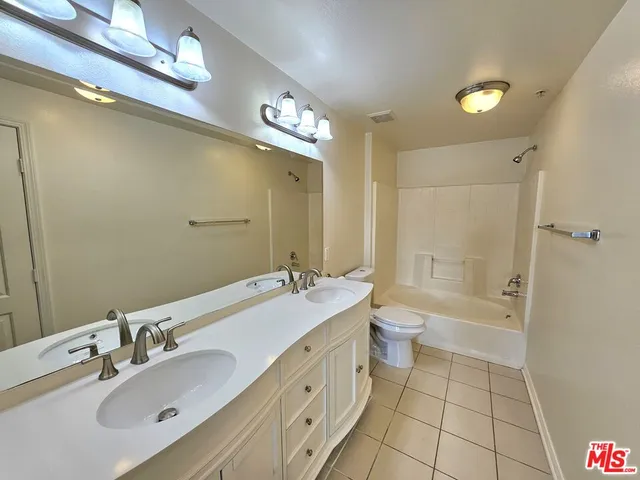 a bathroom with a double vanity sink a toilet and shower