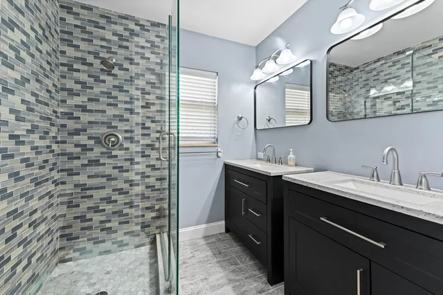 a bathroom with a granite countertop sink a mirror and a shower