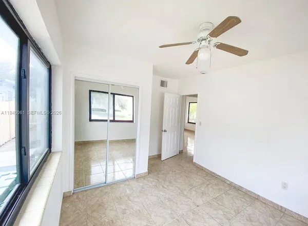 an empty room with windows and fan