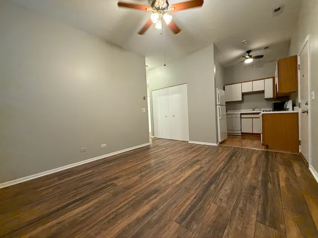 a view of a kitchen with a sink and dishwasher a stove top oven with wooden floor