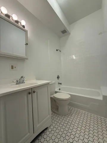 a bathroom with a toilet a sink a mirror a bathtub and vanity