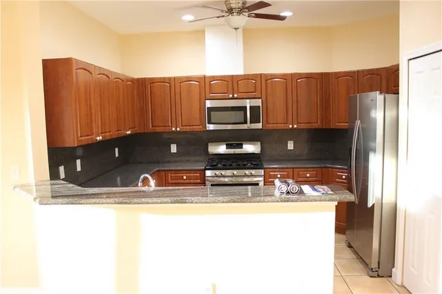 a kitchen with stainless steel appliances granite countertop a sink refrigerator and microwave