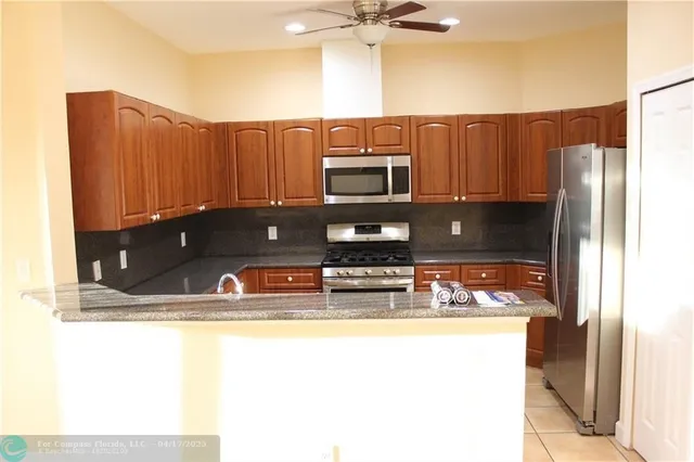 a kitchen with stainless steel appliances granite countertop a sink refrigerator and microwave