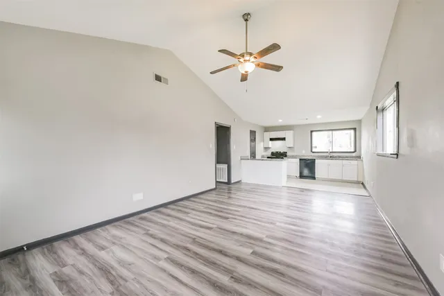 a view of an empty room with window and wooden floor