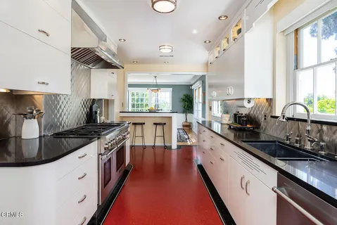 a large white kitchen with stainless steel appliances a sink a stove and a window