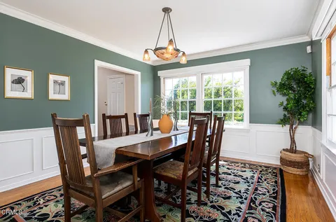 a dining room with furniture potted plants and wooden floor