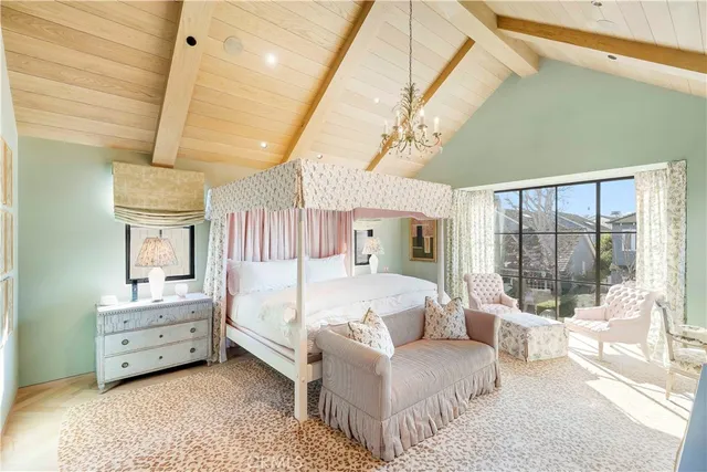 a spacious bedroom with a bed a chandelier and large window