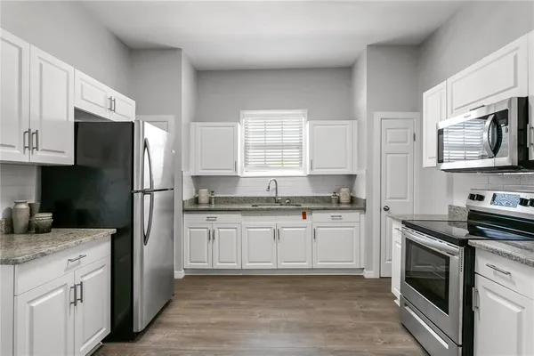 a kitchen with granite countertop a refrigerator stove and sink