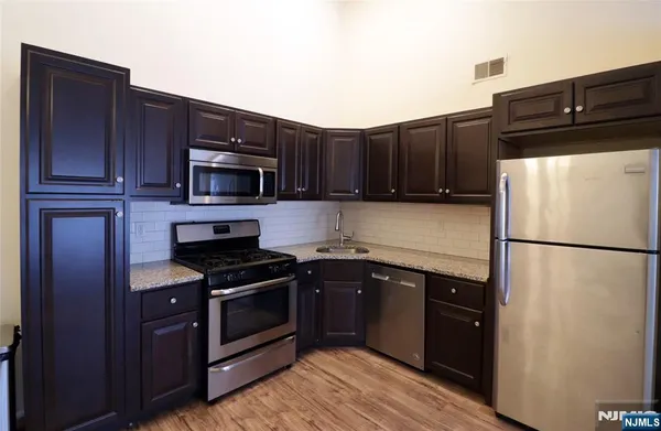a kitchen with granite countertop a refrigerator stove and microwave