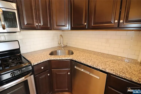 a kitchen with granite countertop a sink stainless steel appliances and cabinets