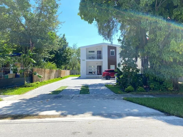 a view of a house with a yard and large trees