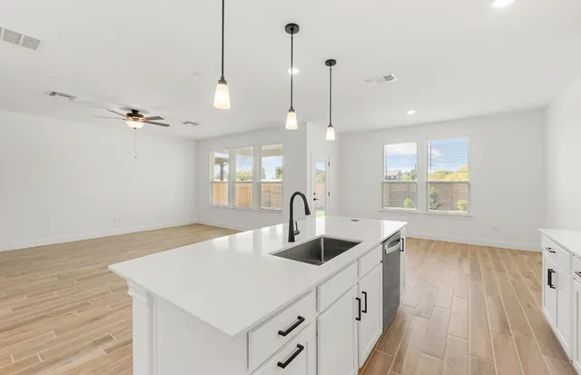 a kitchen with stainless steel appliances granite countertop a sink a stove a refrigerator and island with wooden floor